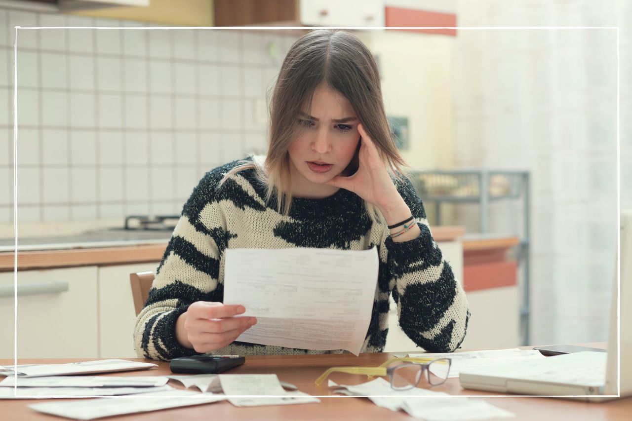 woman sitting at kitchen table looking at household bills