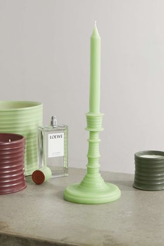 light green standing candle with some loewe accessories nearby