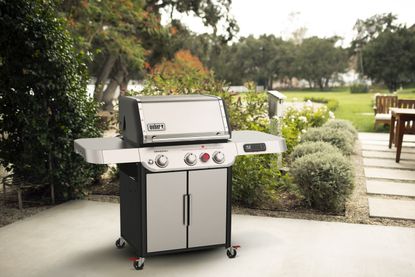 A silver gas grill on a patio of a backyard