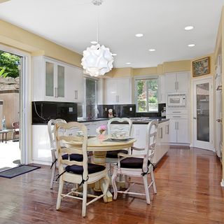 white kitchen with dining table and wooden flooring