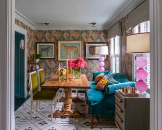 A dining room idea with blue velvet dining sofa, green velvet upholstered chairs and Gucci wallpaper with teal, pink and gold print