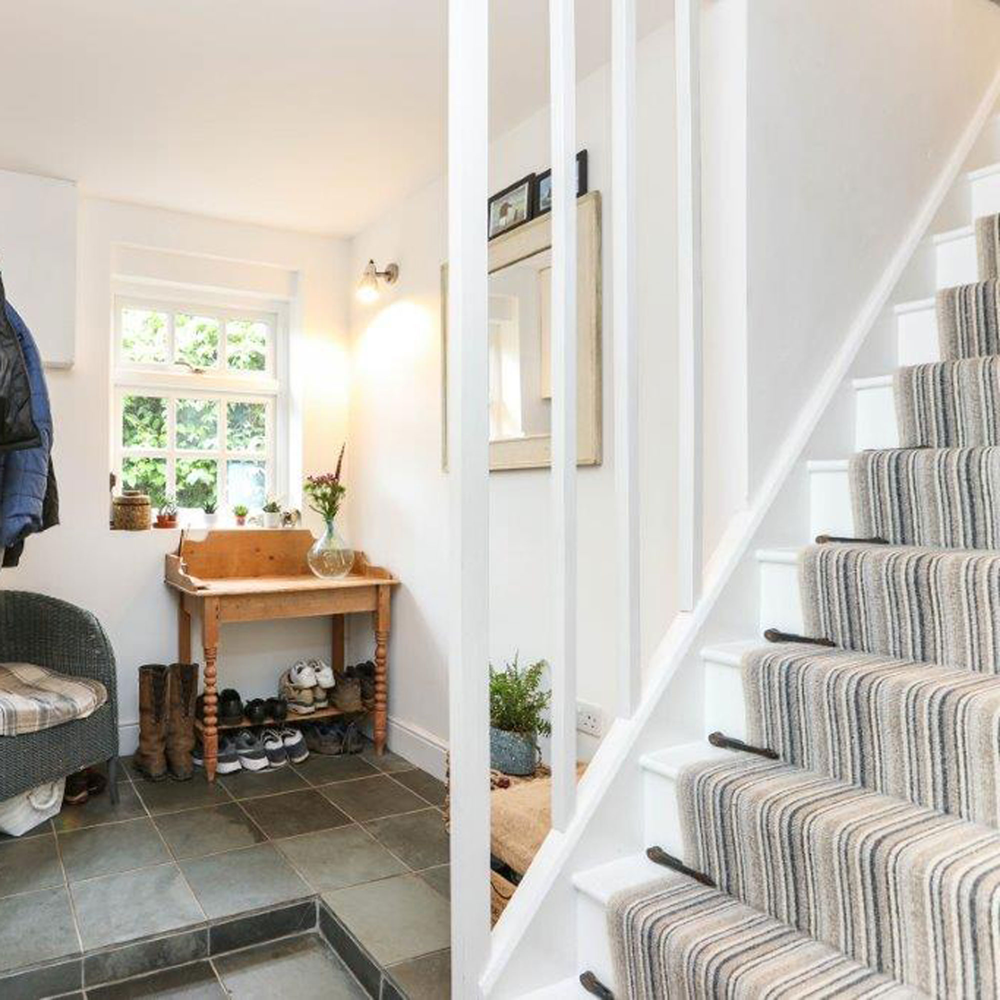 hallway with slate flooring and striped carpet on stairs