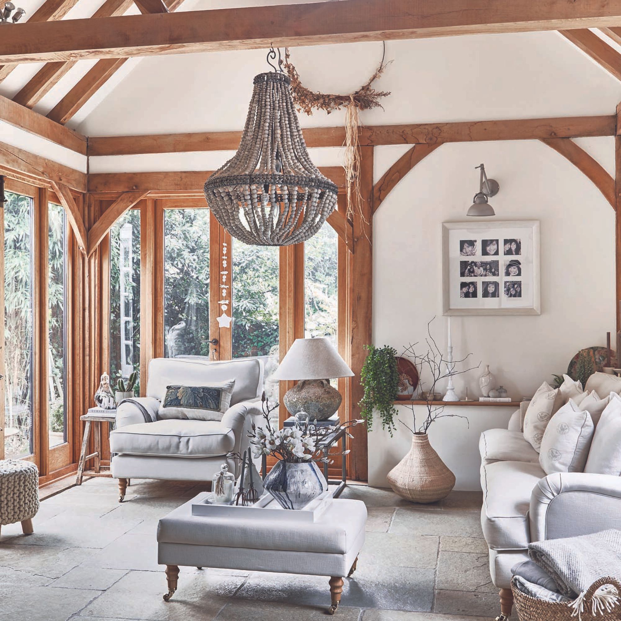 oak framed sunroom with antique beaded pendant light and white sofa and armchair
