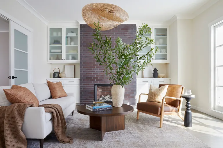 Living room with white walls, French doors, white sofa, tan armchair and dark wood round coffee table on large area rug