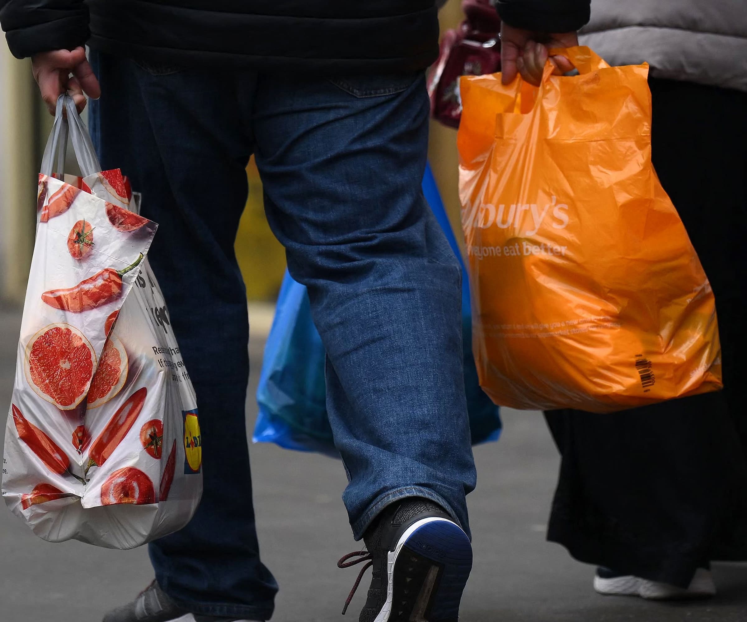 Shoppers carry their purchases in Aldi and Sainsbury&#039;s plastic shopping bags, in east London on February 20, 2023