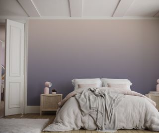 A bedroom with a purple ombre wall