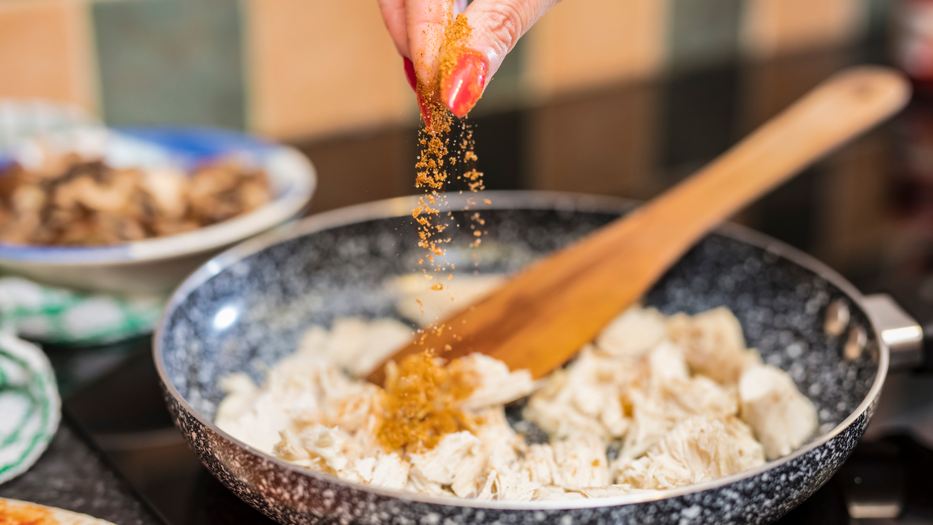 鶏肉にスパイスを加える女性