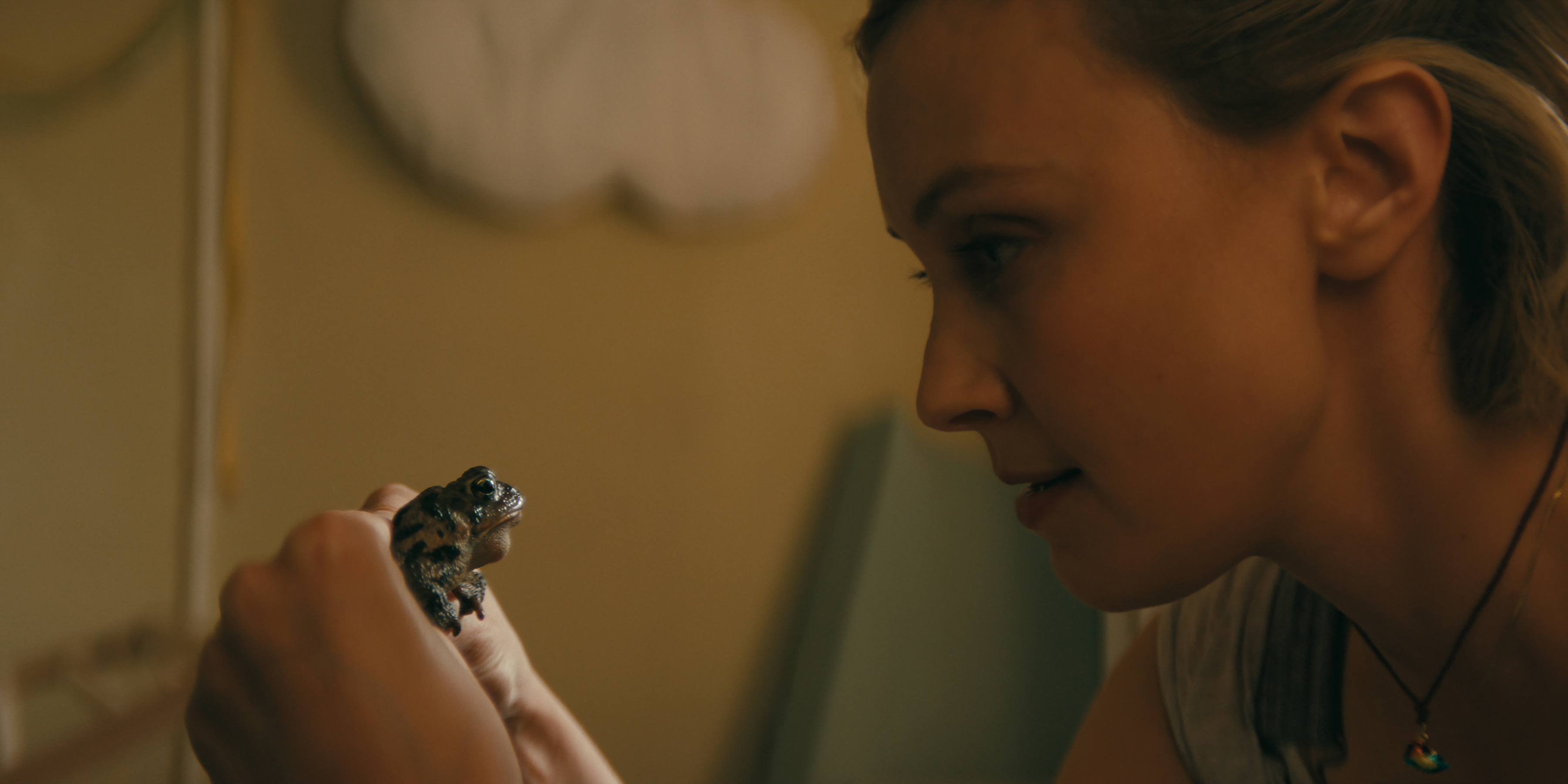 Sarah gordon as laura holding a frog in a still from wayward