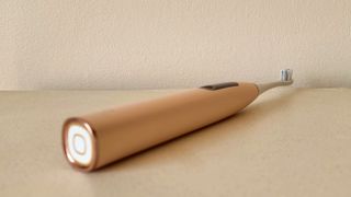 The Oclean X Pro Digital S electric toothbrush laying flat on a beige table