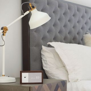 bedroom with grey headboard and white lamp