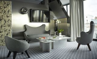 Hotel room with grey chairs, grey patterned carpet and patterned wallpaper