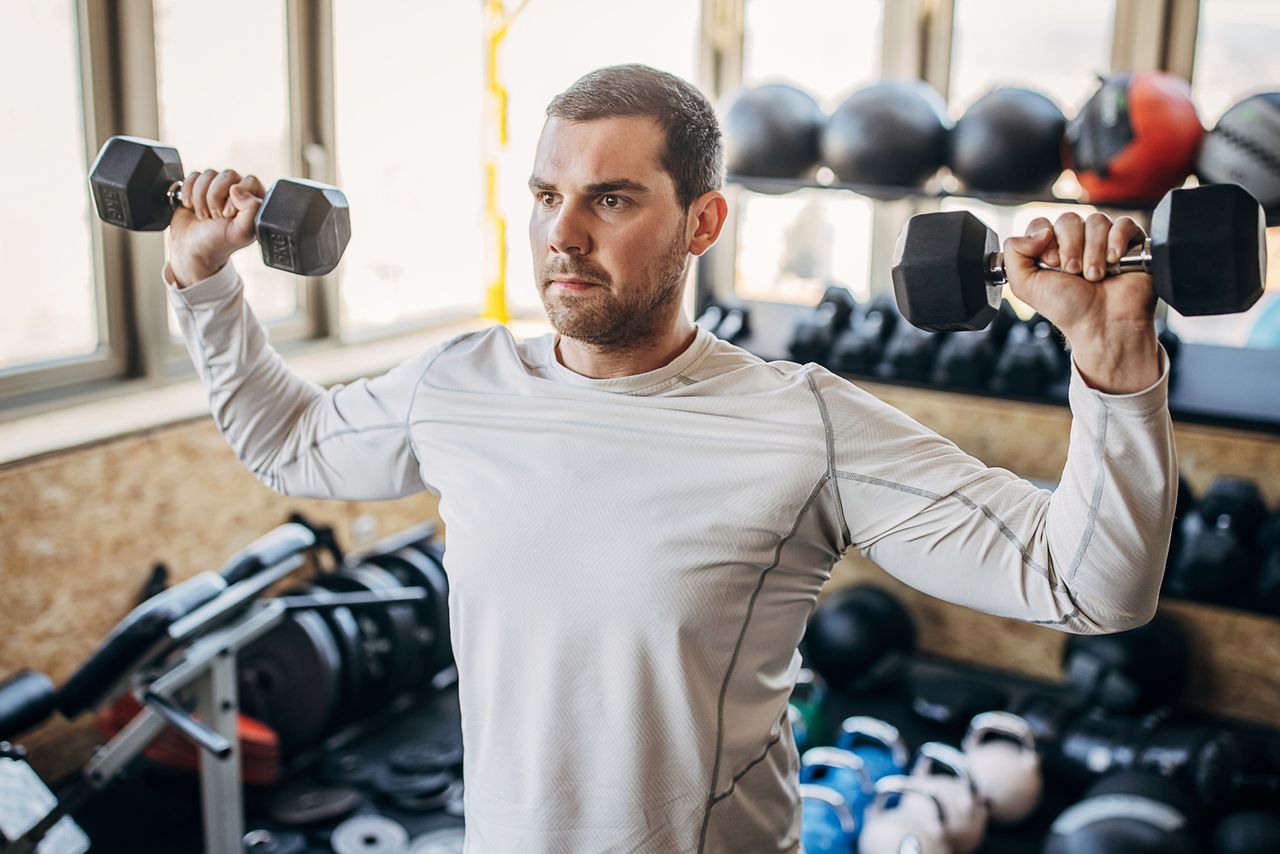 Man doing standing dumbbell workout in a home gym