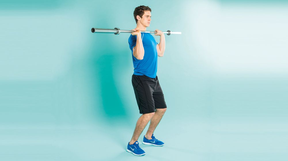 Man demonstrates the midway position of the clean exercise using an empty Olympic barbell