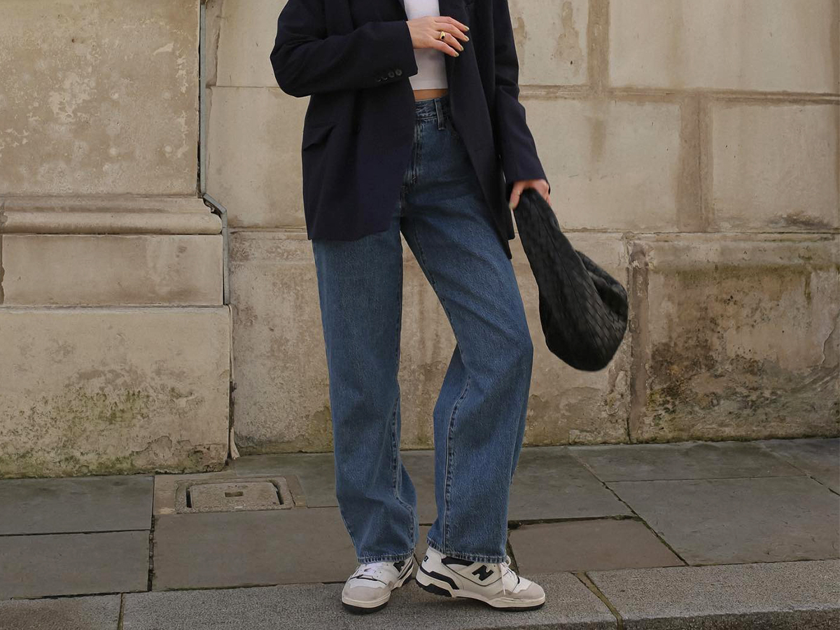 Influencer Francesca Saffari wears Levi jeans, a blazer, and white tee with New Balance sneakers and a woven black bag.