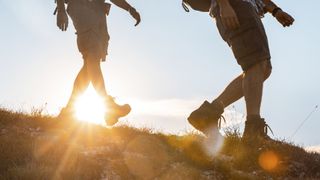 The legs of two men as they hike downhill at sunset