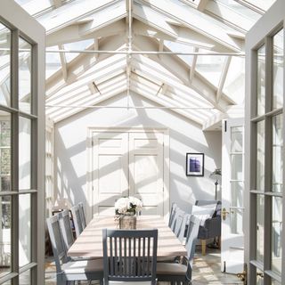 A bright and airy conservatory with a dining table and grey chairs