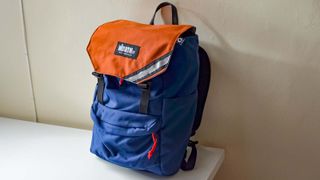 A North St. Belmont in Navy with an Orange flap sitting on a desk