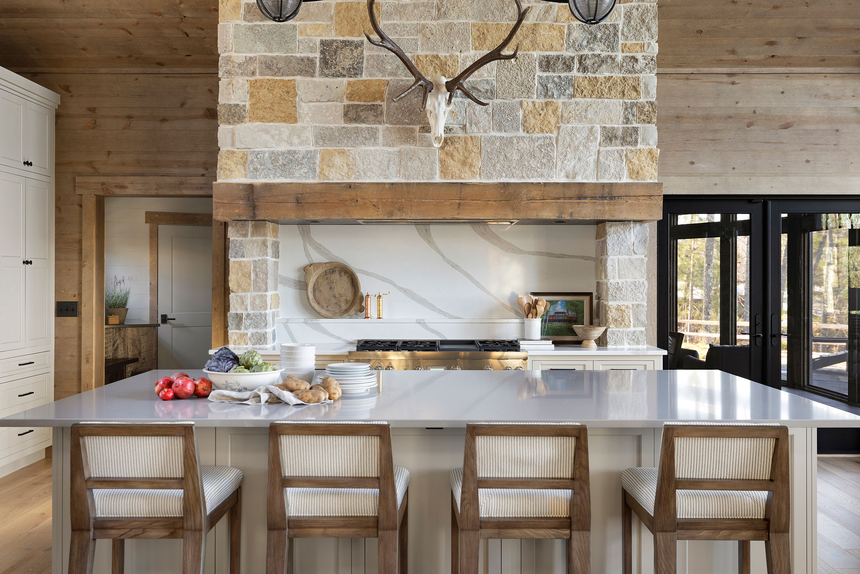 kitchen island with white worktop woven bar stools with backs exposed brick range cooker hood and picture windows
