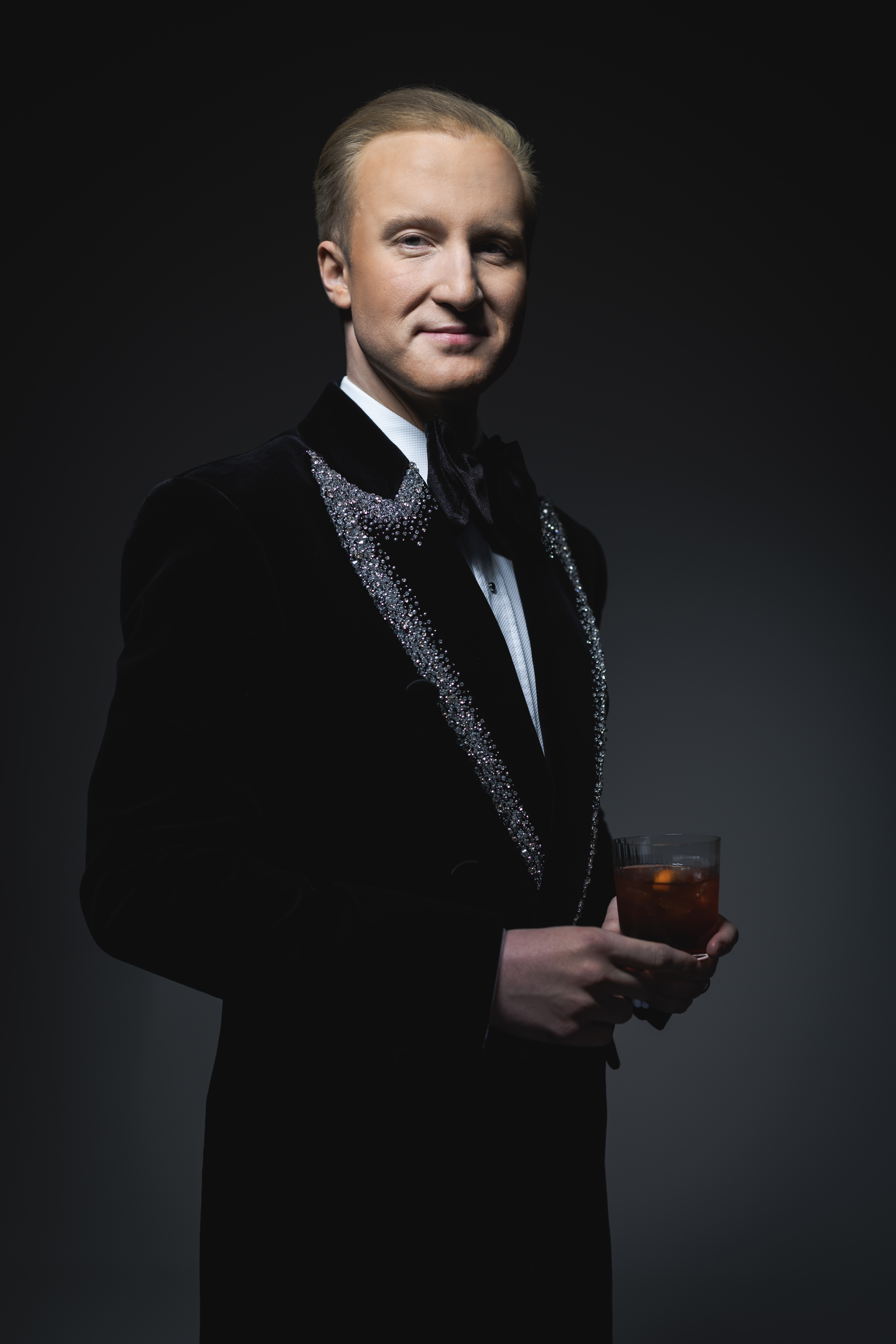 William Hanson wearing a black tuxedo holding a drink