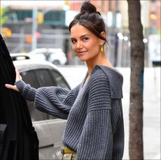 Katie Holmes in a gray sweater and gold pants