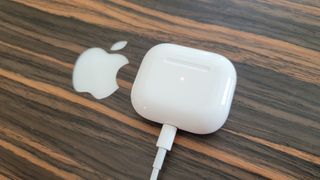 The Apple AirPods 3 connected to a Lightning charging cable