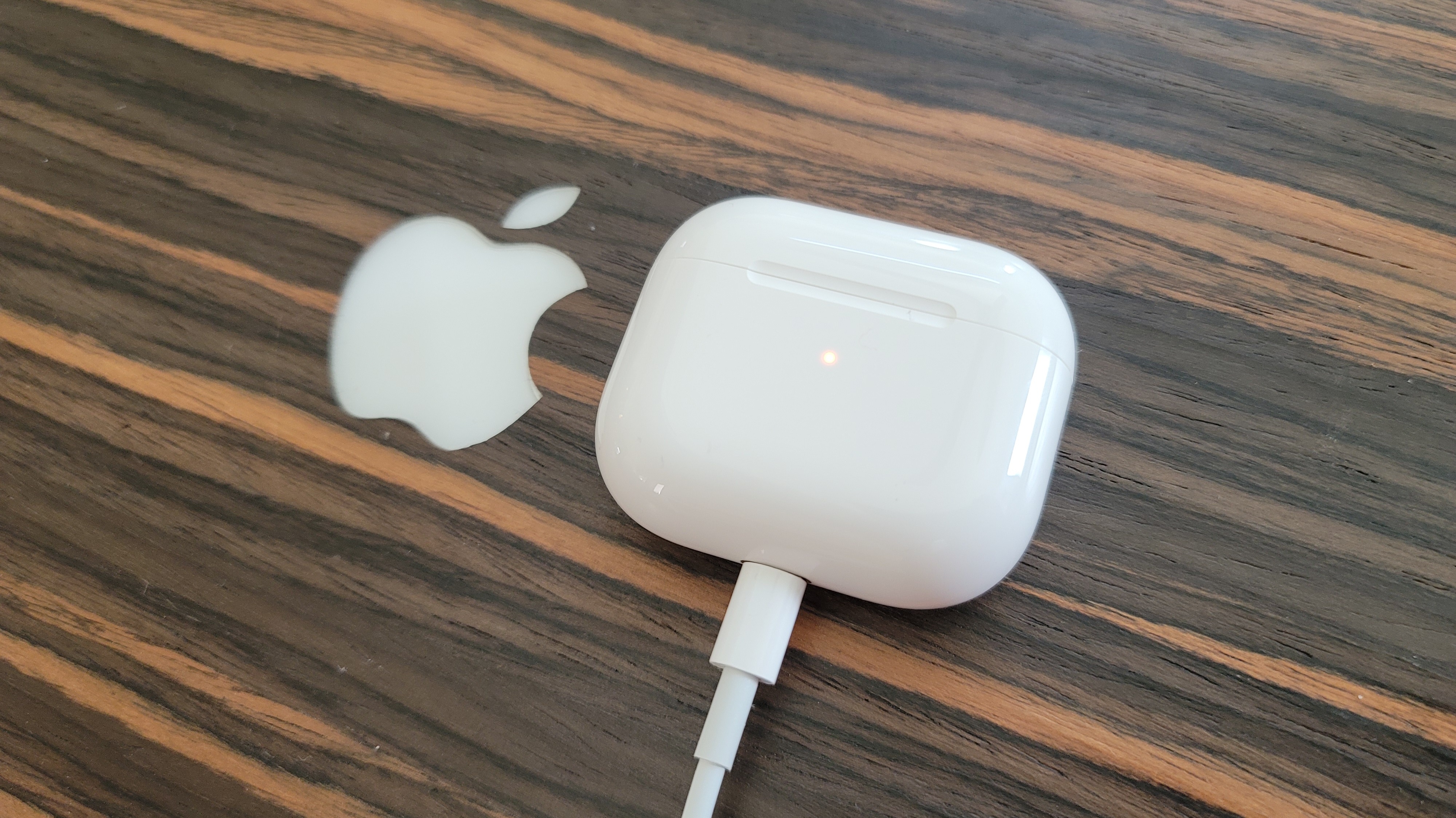 Apple AirPods 3 is connected to a Lightning charging cable