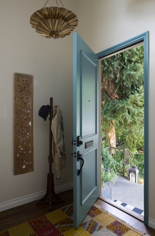 A small neutral entryway with a bold blue front door open