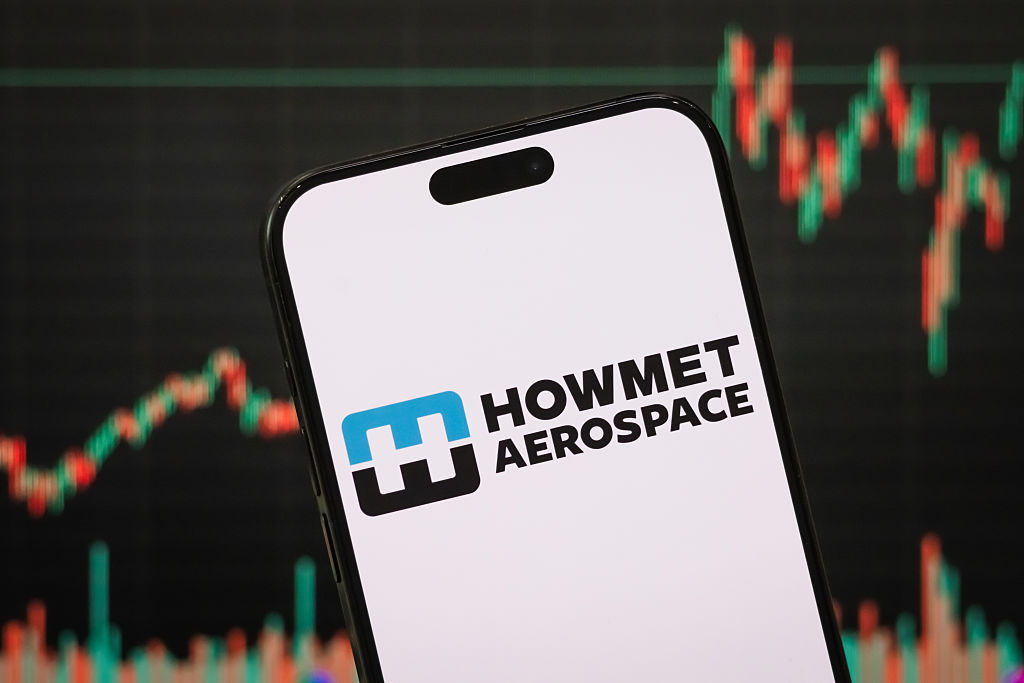 Howmet Aerospace logo on a smartphone with a blurred stock chart in the background