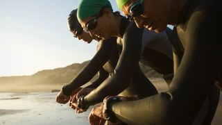Triathletes looking at their watches before jumping in the water