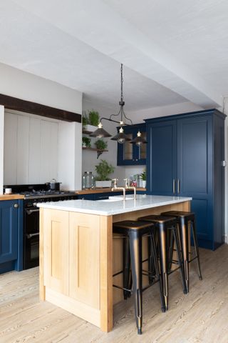 A dark blue shaker kitchen with wood kitchen island with wood bar stools