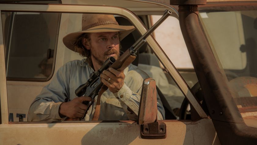 Graham Lawson holding a gun as he stands behind a car door in Territory.