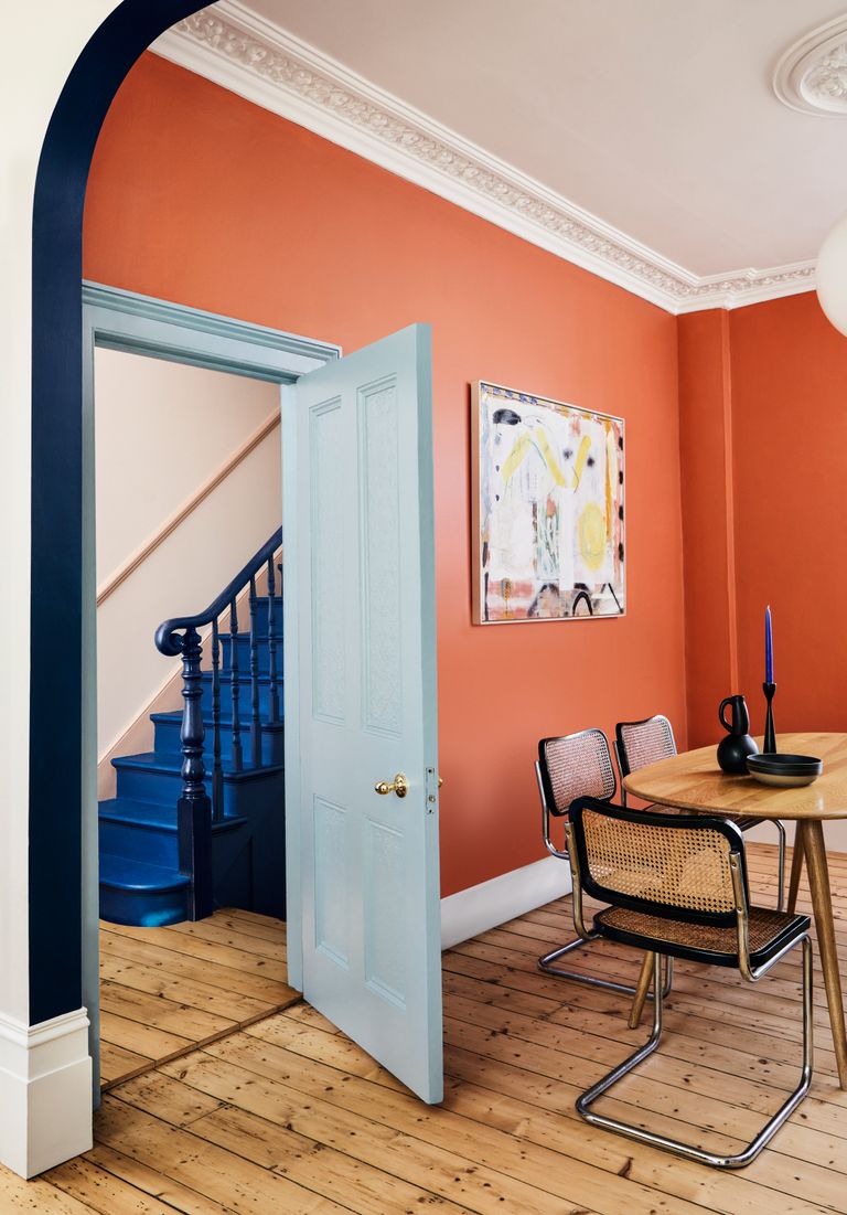 Deep orange dining with with light blue door frame