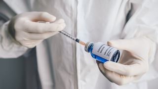 Close-up of scientist hands holding syringe with a sample test bottle of Covid-19 vaccine