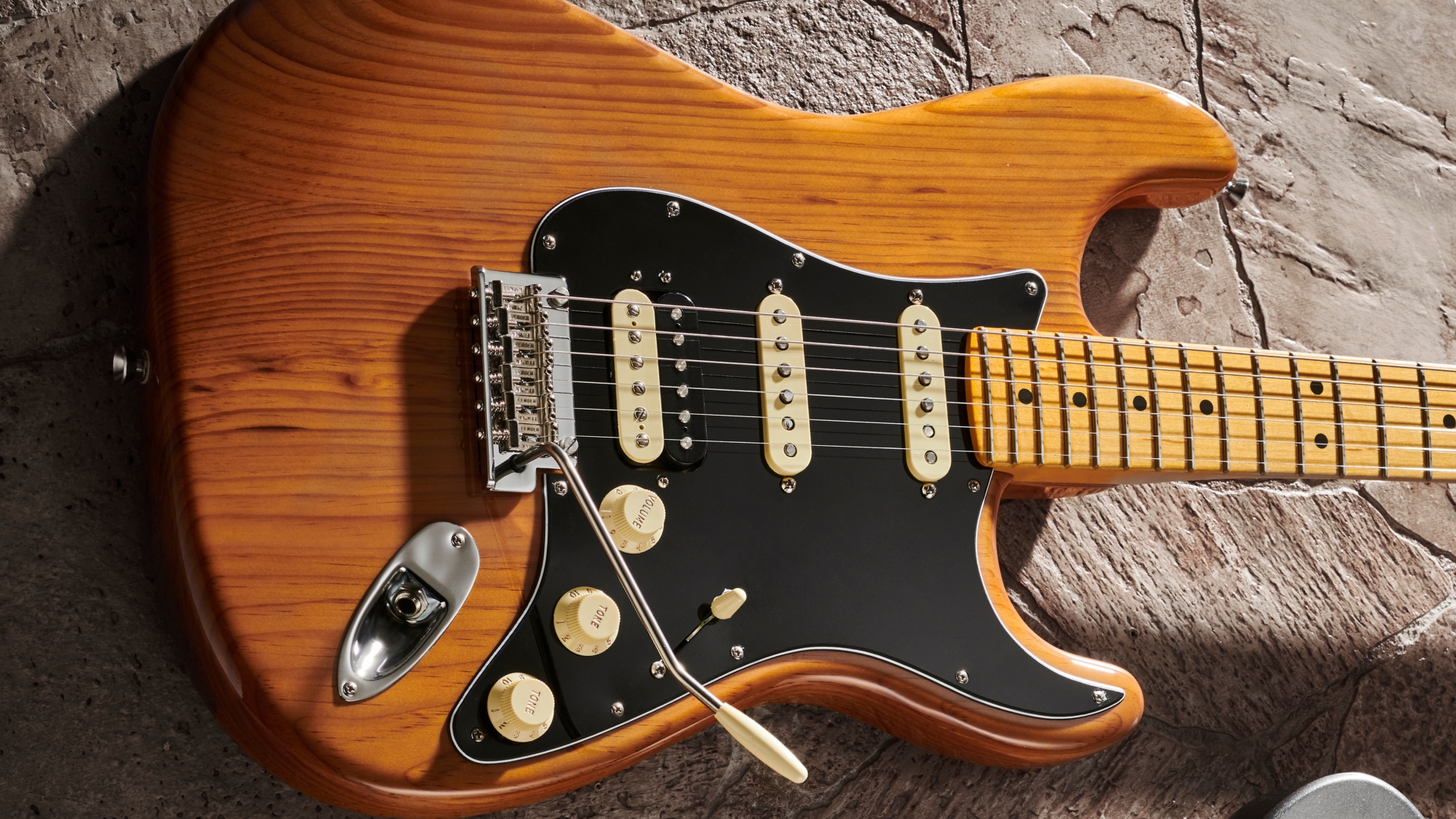 A Fender American Professional II Stratocaster electric guitar lying on a concrete floor