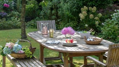 budget backyard ideas wooden table on lawn with picked flowers