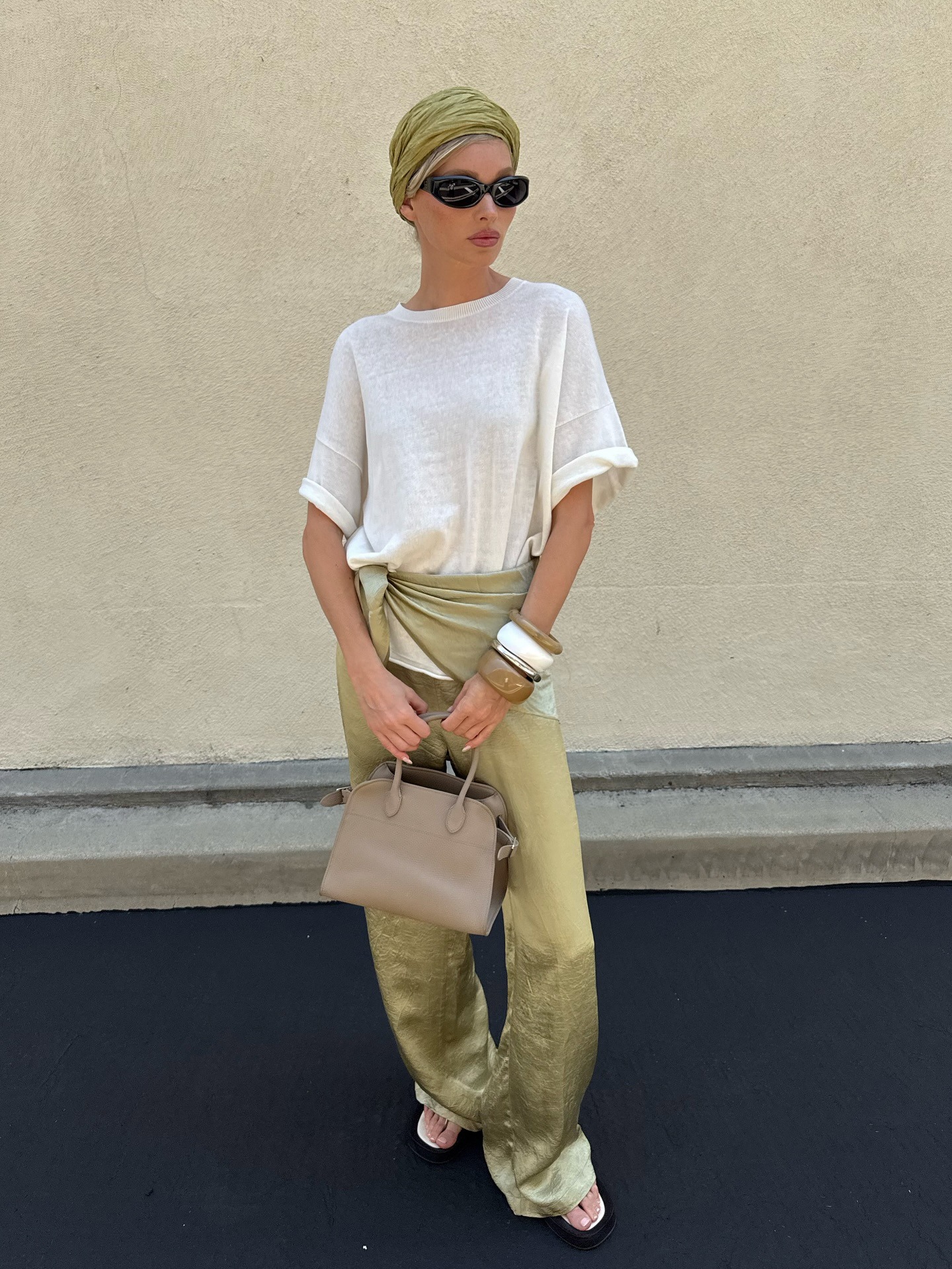 Elsa Hosk wearing a white tee, green satin pants, and a The Row Margaux bag