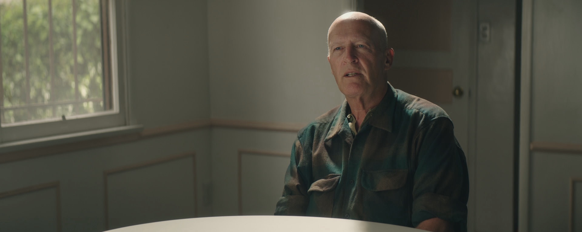 David Sconce sits at a table for a talking head interview in the hbo documentary the mortician