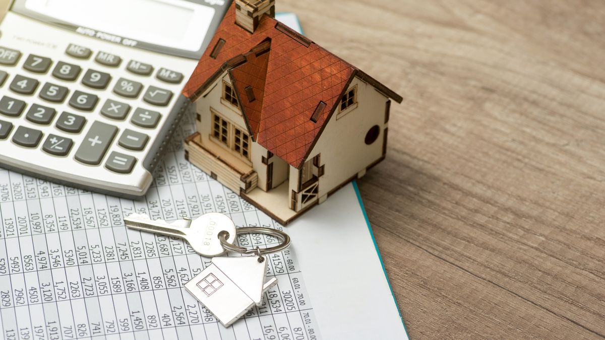 Spreadsheet on wood surface with calculator, model house and key with house fob on top