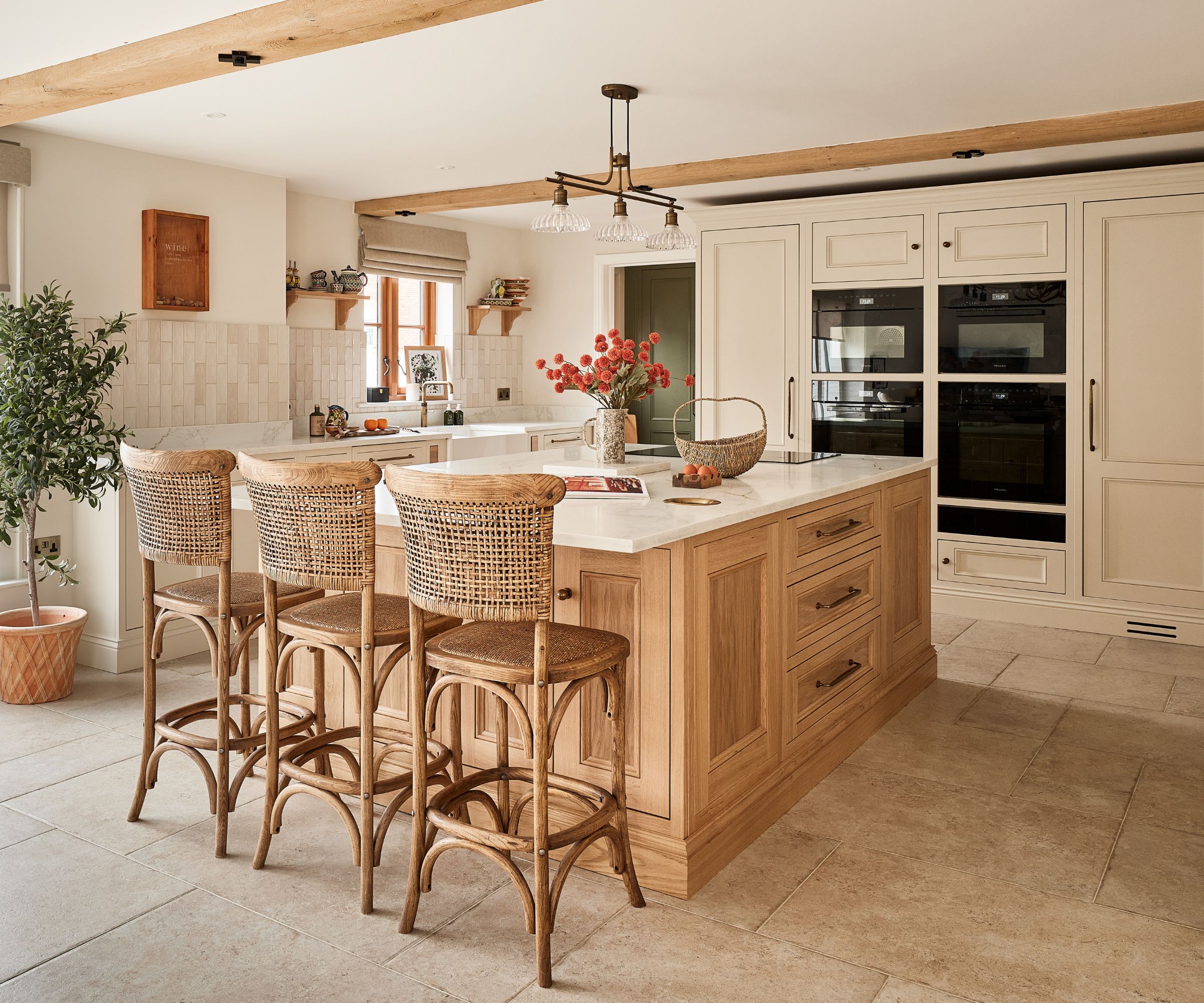 A sociable kitchen with ream cabinets, a wooden island, and tarnishes brass hardware throughout