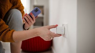 woman uses phone near smart wall plug