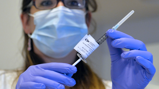 A doctor holds a syringe containing an Ebola vaccine 