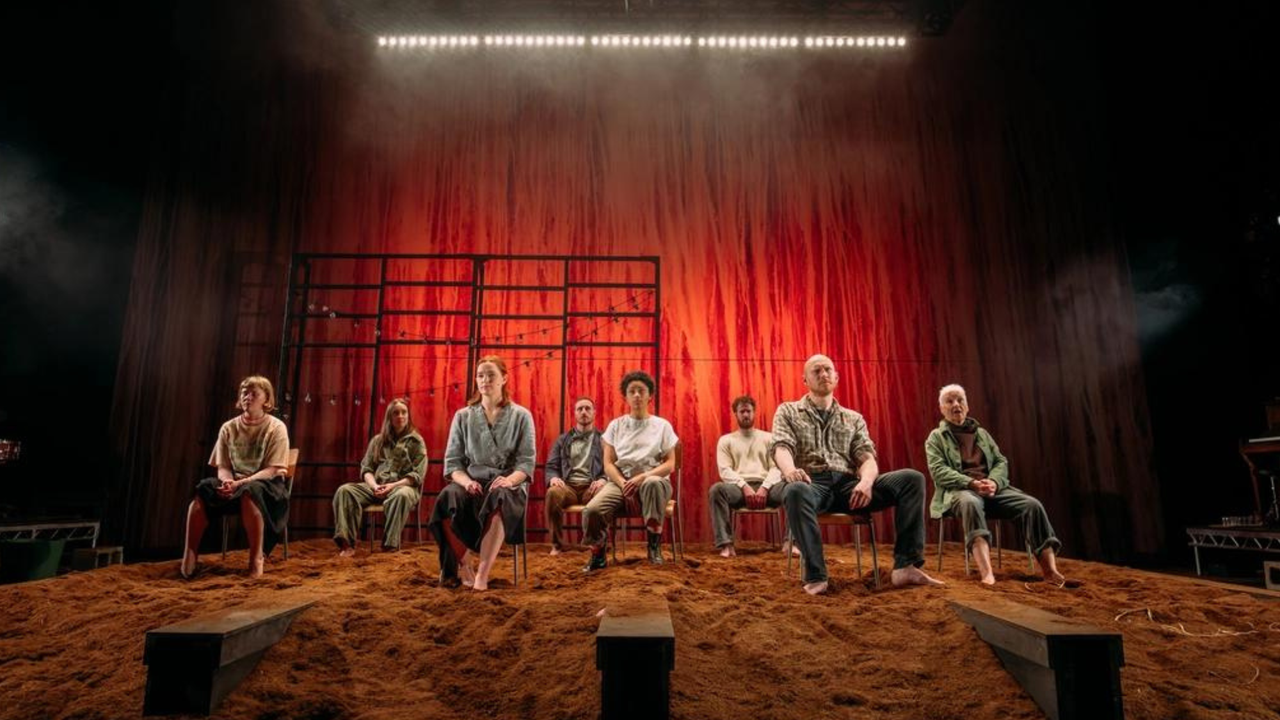 The cast of Sunset Song sit in a row on stage, with Danielle Jam at the front centre.