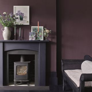 living room paint colours 2023, plum living room with black rattan chaise, purple fire surround, artwork, candles, vases, log burner