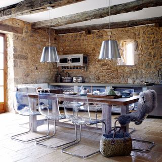 kitchen area with exposed stone wall and beam and dinner table and chairs