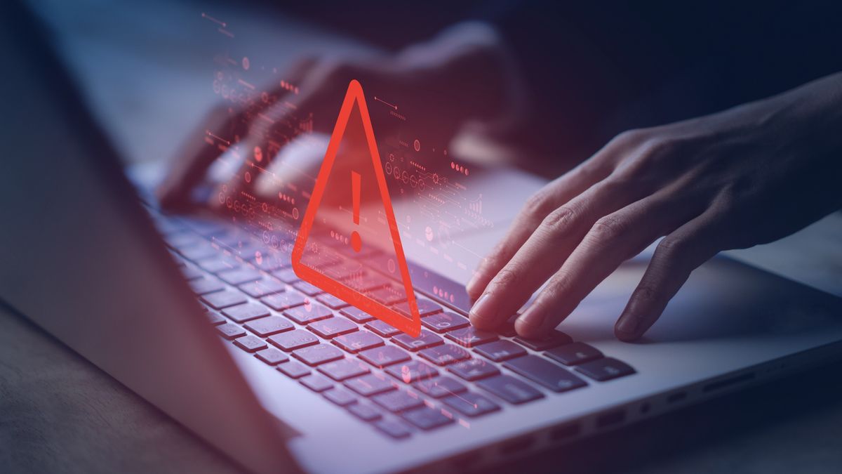 A close up of a person&#039;s hands on a Macbook keyboard with a red exclamation mark overlaid