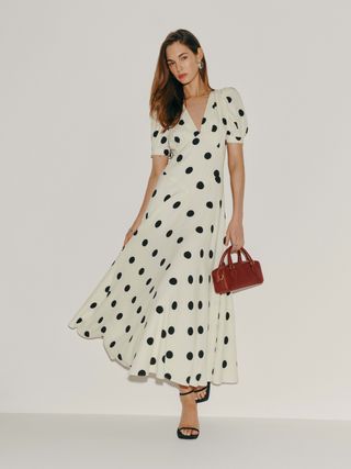 a model wears a short-sleeve polka dot dress in black and white