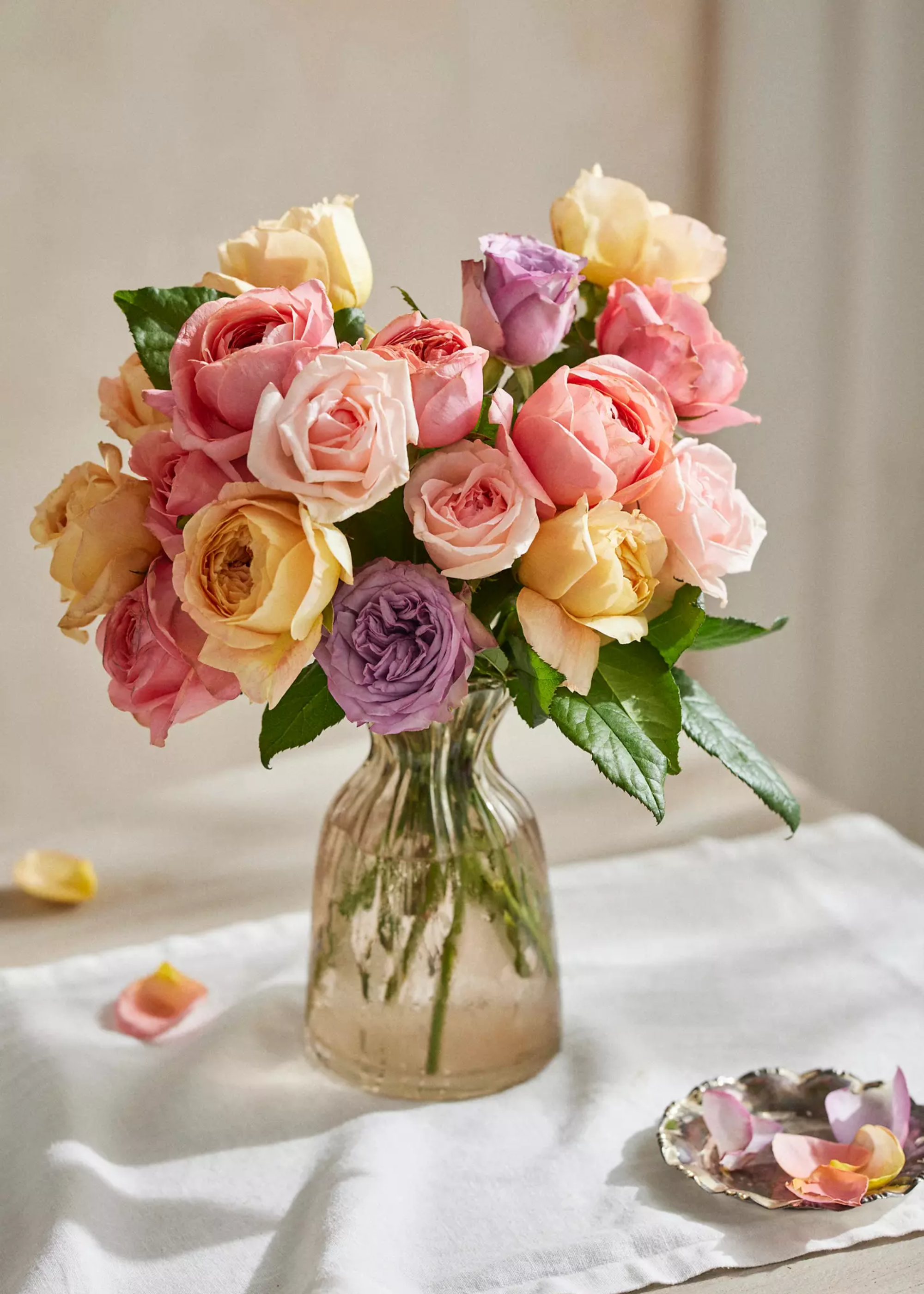 A vase of colorful roses on a side table with a table runner