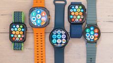 A close-up of five smartwatch on a wooded surface including the Apple Watch SE, Samsung Galaxy Watch Ultra, Google Pixel Watch 3 XL, Apple Watch 10 and Samsung Galaxy Watch 7