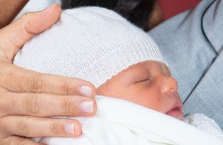 Newborn Prince Archie wearing a white hat and blanket