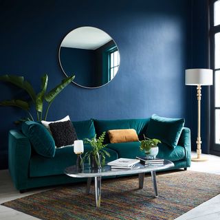 living room with mirror on navy blue wall sofa table and lamp